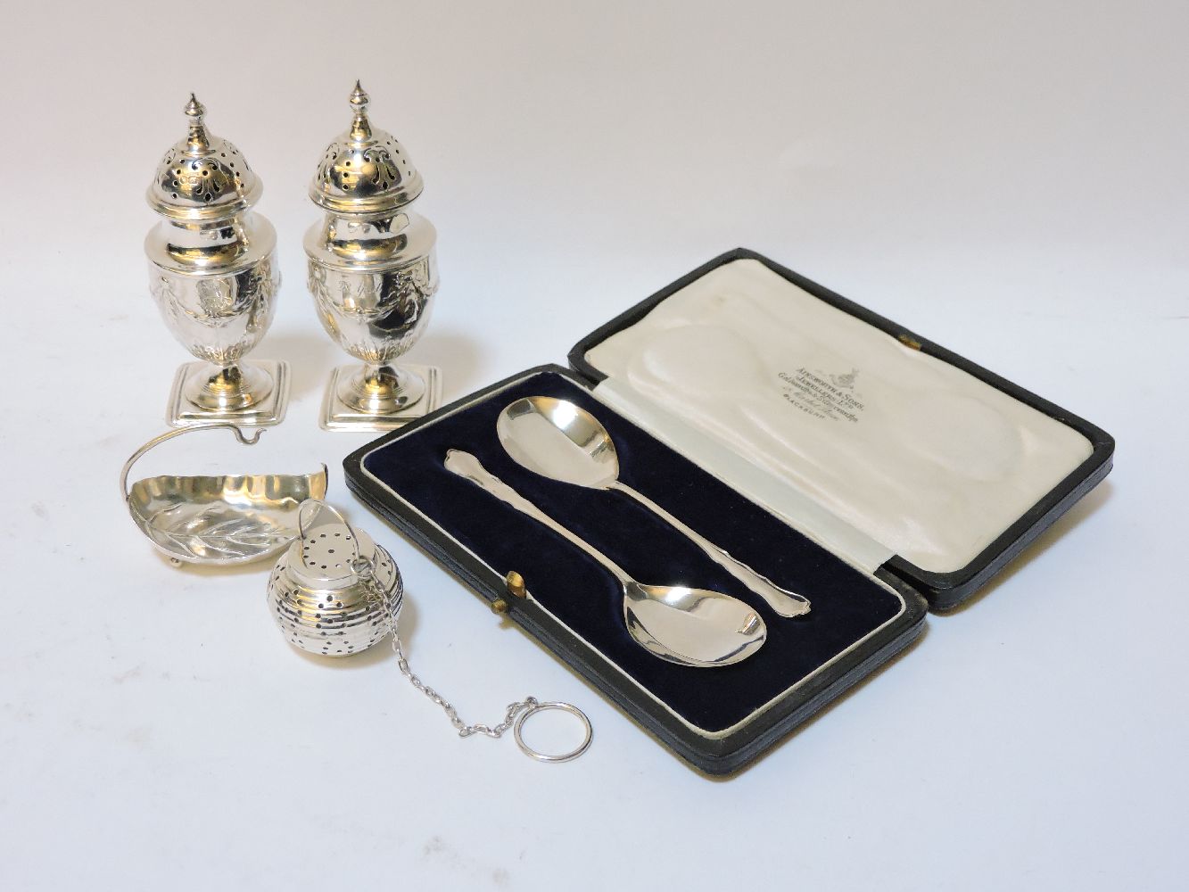 Two silver peppers, of swagged urn form, two silver spoons, cased, and a novelty silver pomander