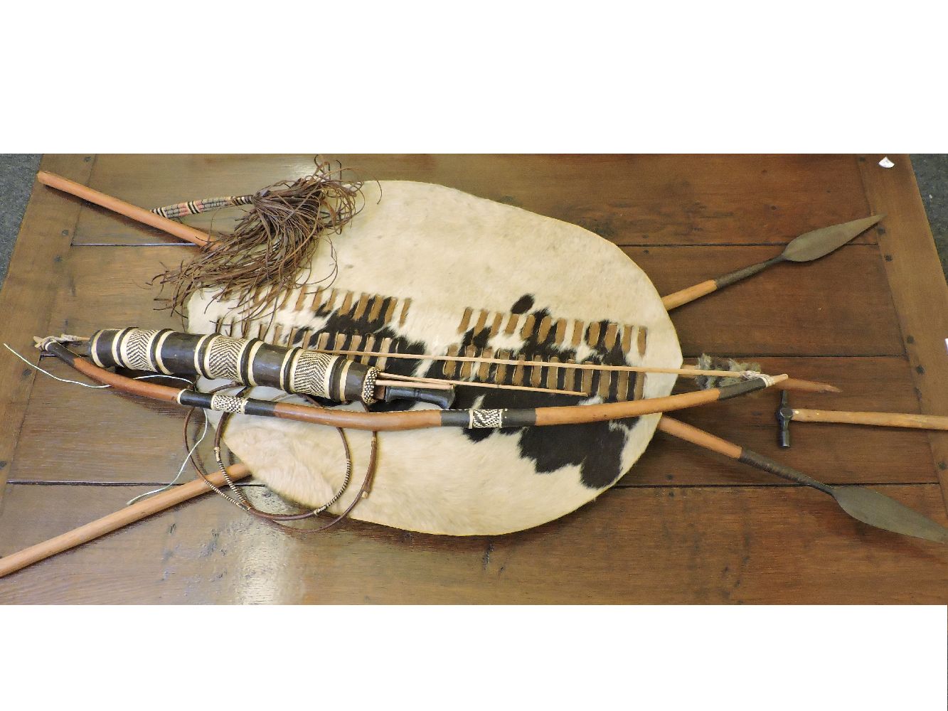 Two modern Zulu spears, a hide shield, arrows in a quiver, bow and fly whisk