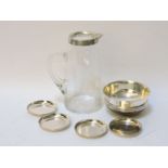 A silver mounted glass jug, a small wooden and silver mounted bowl, and four silver pin dishes