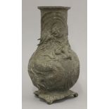 A late 19th century bronze vase, sculpted in vigorous style with a dragon amongst swirling waves