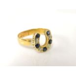 A gold diamond and sapphire horse shoe, mounted onto a later wedding ring, band only tested as 22ct