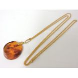 A Russian Art Deco amber pendant, with rolled gold bale, on a gold chain, original box