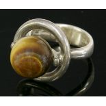 A Danish sterling silver tiger's eye ring,by Hans Hansen, with a tiger's eye bead, peg set to the