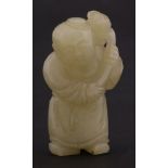 A jade Carving,19th century, of a boy holding a lotus, the stone a mottled grey-green throughout,