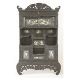 A carved blackwood Cabinet, c.1900, surmounted by a hawk above a series of sliding cupboard doors
