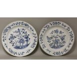 A pair of blue and white Dishes,early 18th century, each painted with flowers and a rock in a garden