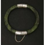 A spinach jade bangle, 20th century, of rounded form with metalwares hinge and clasp, 6.3cm inner