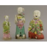 Three famille rose figures, early 19th century, each an immortal or a boy holding a musical