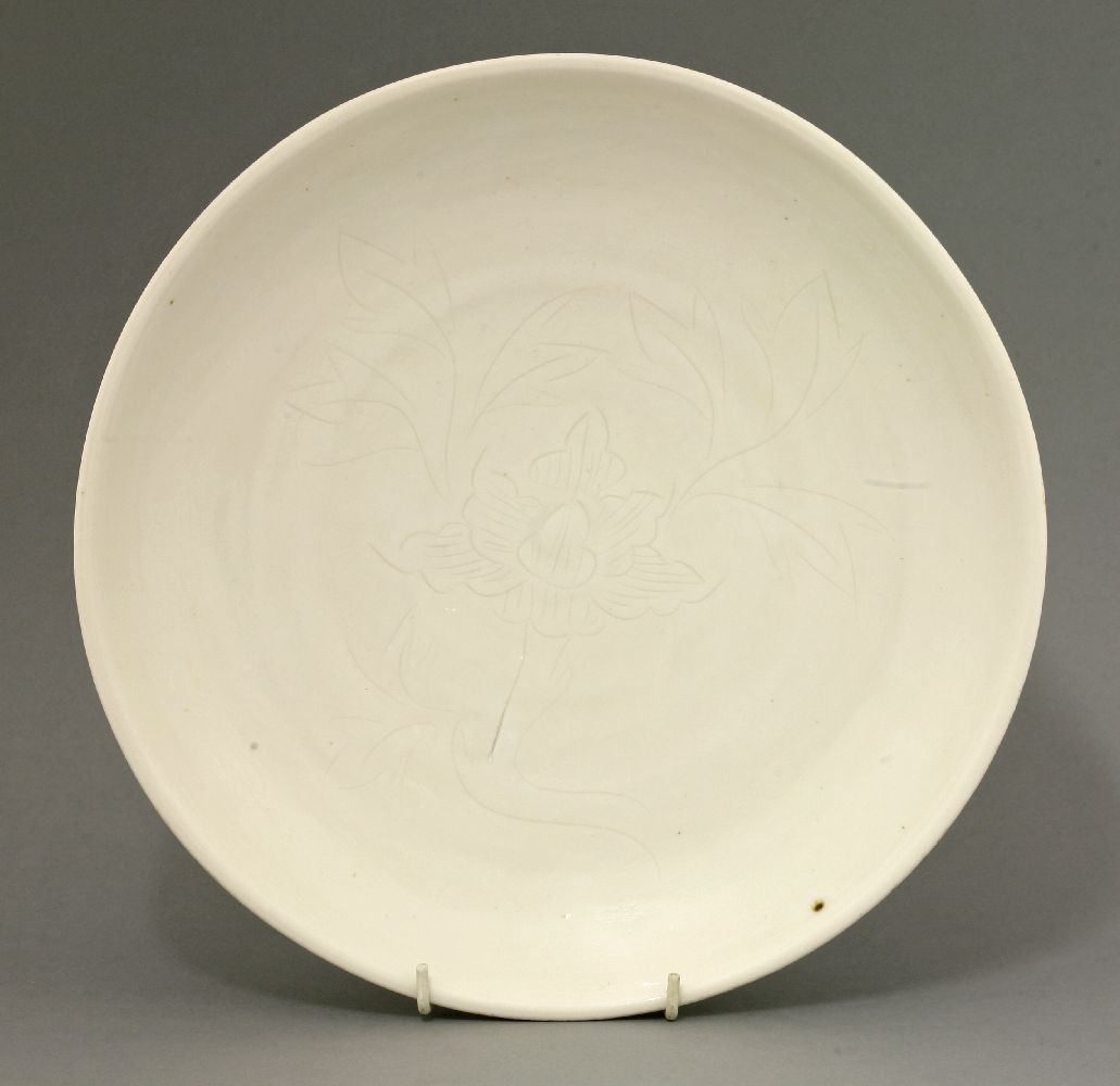 A blanc de Chine circular Saucer Dish,17th century, the front incised with a flowering bloom,29cm