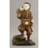A wood and ivory Figure,late 19th century, of a man, his clothes of engraved wood with mon and