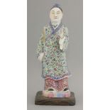 A Chinese famille rose figure, c.1930, his front hand raised and dressed in floral decorated