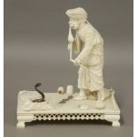 An Indian carved ivory Figure,c.1900, of a snake charmer standing on a rectangular dais with pierced