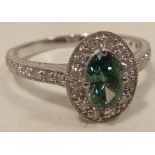 An 18 carat white gold Ring set with a green diamond marquis shaped centre stone surrounded by