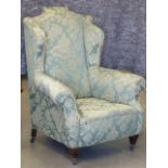 An Edwardian upholstered wing back Armchair in early 18th Century style, raised on square,