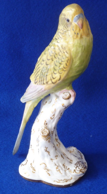 A Royal Worcester porcelain Model of a green and yellow Budgerigar perched on a tree stump,