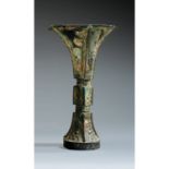 VASE GUen bronze de patine sombre croûteuse, monté sur un haut pied élargi, à petite panse