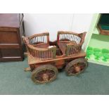 A late 20th Century, Indian hardwood and brass mounted, child's carriage. fitted face to face seats