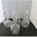 A group of eight clear glass decanters with stoppers