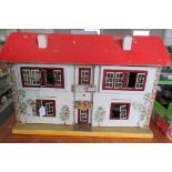 An early 20th Century painted wood dolls' house containing some furniture.