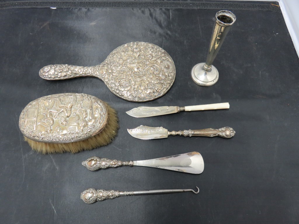 A silver backed dressing table hand mirror, a silver bud vase, silver handled shoe horn and button