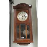 A 20th Century oak cased wall clock with bevelled glass door