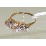 A 9ct gold three stone clear paste set ring. The large stones in cage mount and claw set. Ring