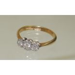 An 18ct gold and platinum three stone illusion set diamond ring, size M+.