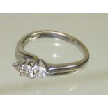 A ladies 18ct white gold, three stone diamond crossover ring. The diamonds 1/8th carat each