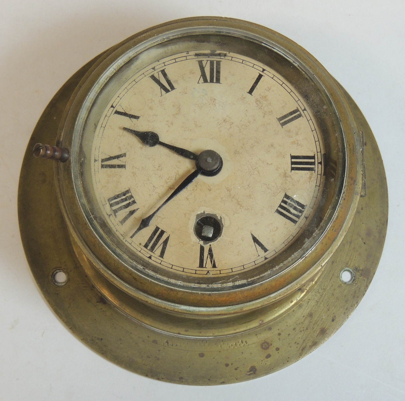 A WWII period bulkhead timepiece having white dial with black Roman numerals and brass casing,