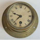 A WWII period bulkhead timepiece having white dial with black Roman numerals and brass casing,