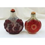 2 CHINESE CARVED RED OVERLAY GLASS SNUFF BOTTLES WITH HARDSTONE STOPPERS LARGEST 8CM TALL