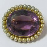19TH CENTURY BROOCH SET WITH AN OVAL AMETHYST WITH A SURROUND OF HALF PEARLS