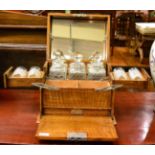 An early 20th century blond oak tantalus cabinet, set with three hobnail cut decanters and with