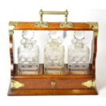 An oak three bottle tantalus Good overall condition. Don't appear to be any losses to decanters