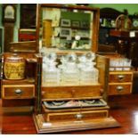 An early 20th century blond oak tantalus/smokers cabinet, fitted with three decanters, six tots,