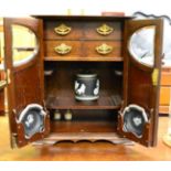 An early 20th century oak smokers cabinet enclosed by two partially glazed panelled doors, fitted