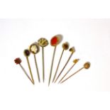A group of nine stick pins comprising: shell cameo set, coral set, 15ct and six other gem set