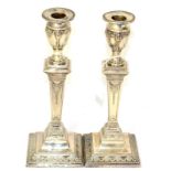 A pair of silver candlesticks with embossed decoration
