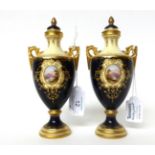 * A pair of Coalport blue ground twin-handled urn shaped vases and covers, with landscape panels,