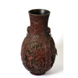 A Chinese cinnabar lacquer vase, Qing Dynasty, of ovoid form, the flared neck with mask handles,