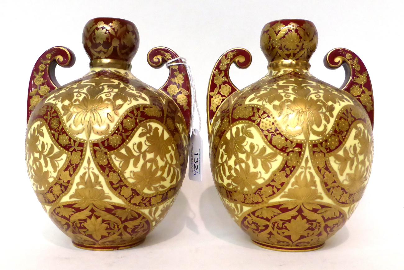 * A pair of Royal Crown Derby cream and claret ground twin-handled vases, gilt with Persian