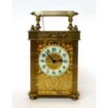 * A brass carriage timepiece, circa 1900, carrying handle, glazed pierced side panels, enamel Arabic