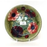* A Moorcroft pottery plate, decorated with anenomies on a green ground, signed, 22cm diameter
