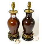 A pair of brown glazed table lamps on hardwood stands, 30cm high