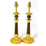 A pair of parcel gilt bronze candlesticks, the urn shaped sconces over foliate capitals, fluted