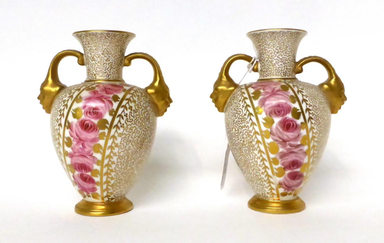 * A pair of Royal Crown Derby porcelain twin-handled vases painted with pink roses on a gilt ground,