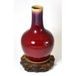 A 19th century Chinese Sang de Boeuf bottle vase, 30cm high, hardwood stand