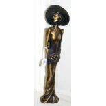 A 20th century bronze of a lady in wide brimmed hat, holding bouquet of flowers, bearing signature