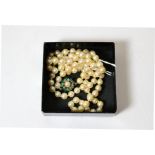 A cultured pearl necklace with an emerald set clasp (one stone missing)