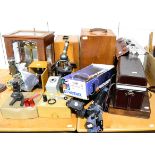 A group of scientific instruments including microscopes, chemical scales, tripods and cases
